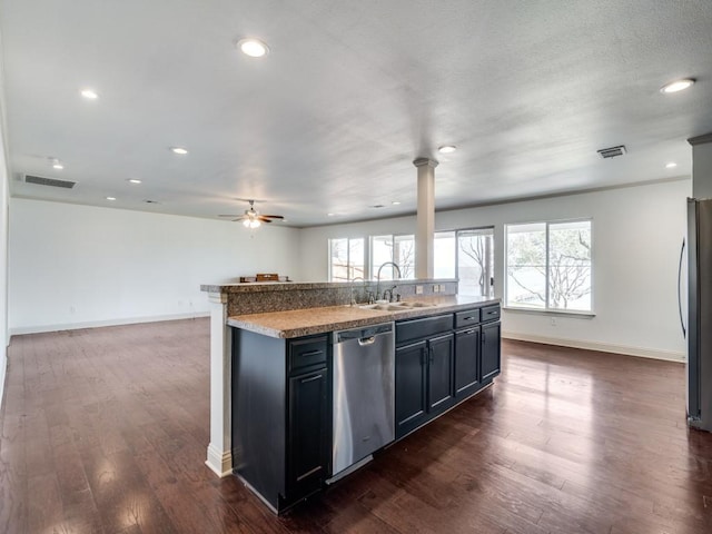 kitchen with dark wood-type flooring, sink, a center island with sink, appliances with stainless steel finishes, and ceiling fan