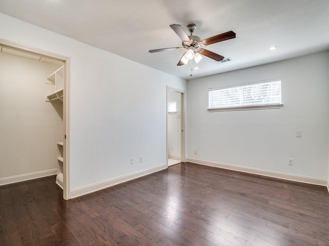 unfurnished bedroom featuring a walk in closet, dark hardwood / wood-style floors, and ceiling fan