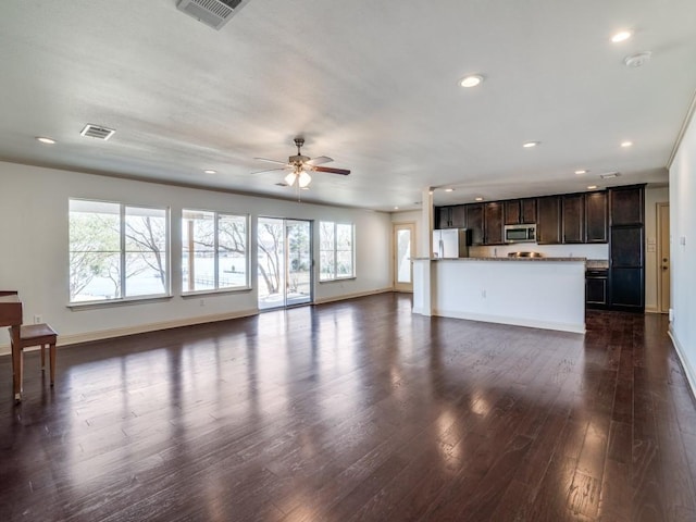 unfurnished living room with ceiling fan, a wealth of natural light, and dark hardwood / wood-style flooring