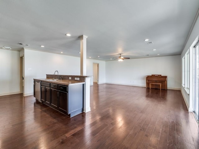 kitchen with sink, ceiling fan, dark hardwood / wood-style floors, dark brown cabinetry, and an island with sink