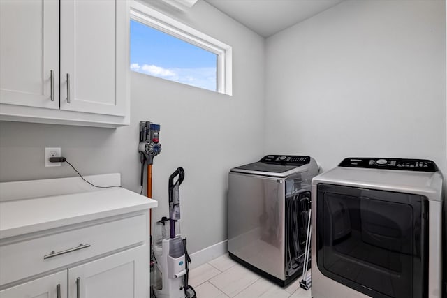 clothes washing area featuring cabinets and separate washer and dryer