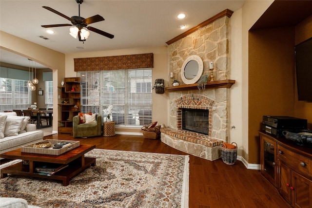 living room featuring ceiling fan, a healthy amount of sunlight, a fireplace, and dark hardwood / wood-style flooring