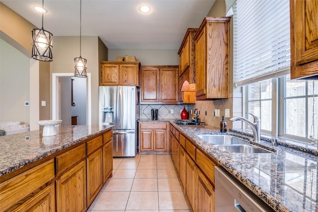 9720 Birdville Way, Fort Worth, TX 76244 - kitchen featuring appliances with stainless steel finishes, a sink, brown cabinets, decorative backsplash, and dark stone countertops