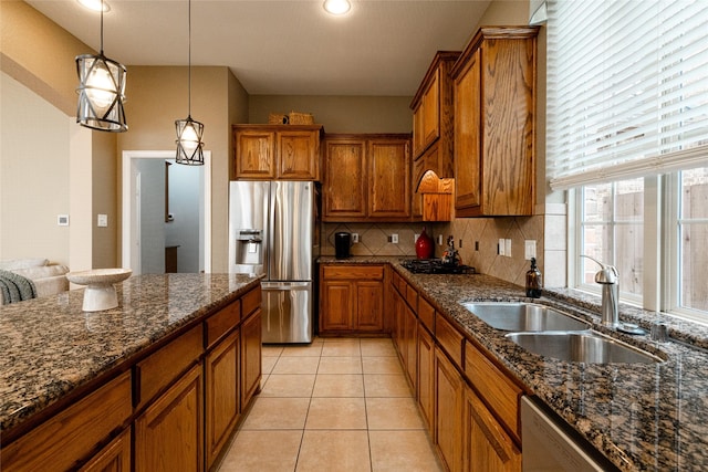 kitchen with sink, tasteful backsplash, decorative light fixtures, dark stone countertops, and appliances with stainless steel finishes