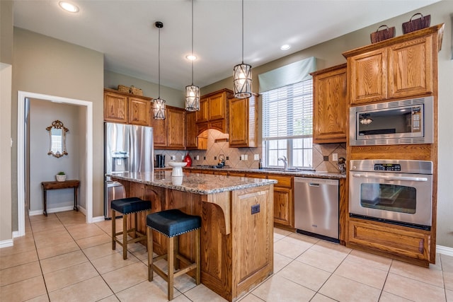 9720 Birdville Way, Fort Worth, TX 76244 - kitchen featuring stainless steel appliances, brown cabinets, dark stone counters, tasteful backsplash, and a kitchen island