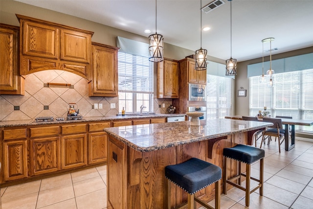 9720 Birdville Way, Fort Worth, TX 76244 - kitchen featuring appliances with stainless steel finishes, brown cabinets, a kitchen island, decorative backsplash, and recessed lighting