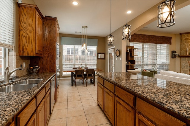 kitchen with light tile patterned flooring, sink, tasteful backsplash, decorative light fixtures, and dark stone countertops