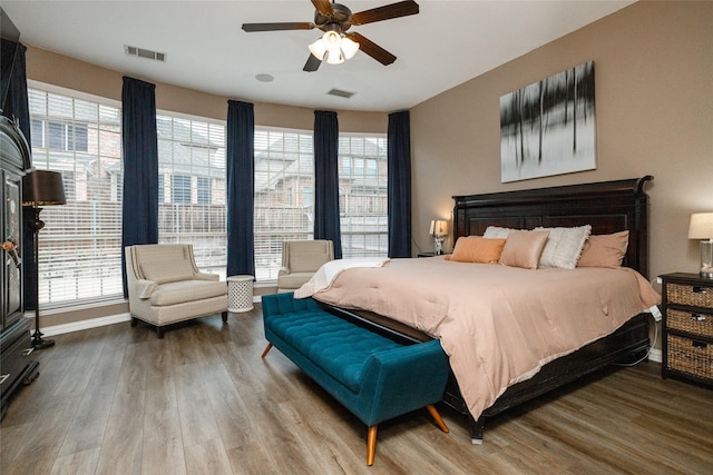 bedroom with multiple windows, hardwood / wood-style floors, and ceiling fan