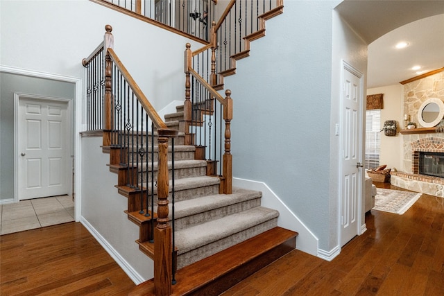 stairs with hardwood / wood-style flooring, a high ceiling, and a fireplace