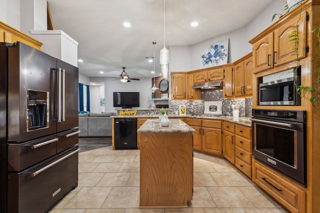 kitchen featuring pendant lighting, backsplash, a center island, light stone counters, and stainless steel appliances