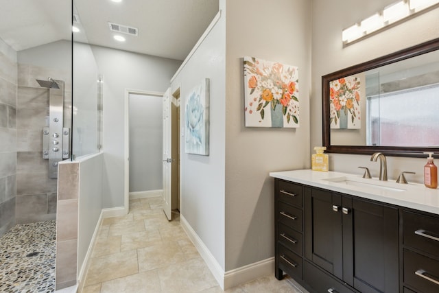 bathroom with vanity, lofted ceiling, and tiled shower