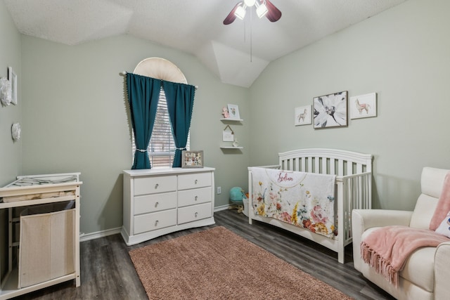 bedroom with a nursery area, ceiling fan, lofted ceiling, and dark hardwood / wood-style flooring