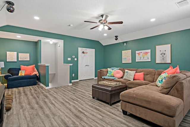 living room featuring vaulted ceiling, a textured ceiling, ceiling fan, and light hardwood / wood-style floors