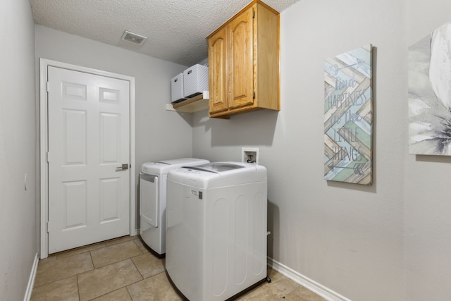 laundry area with cabinets, light tile patterned floors, a textured ceiling, and independent washer and dryer