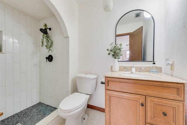 bathroom with vanity, toilet, and tiled shower