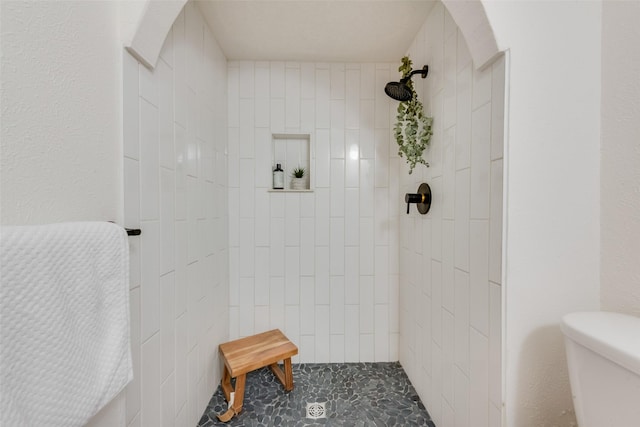 bathroom with a tile shower and toilet