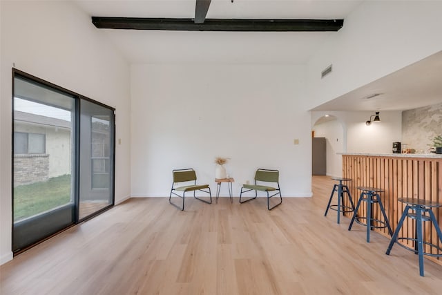 living area with beamed ceiling, indoor bar, high vaulted ceiling, and light hardwood / wood-style flooring