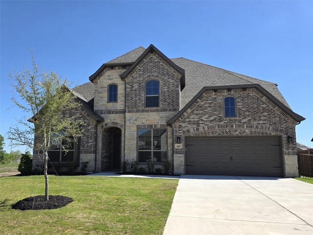 french country home with a front lawn, driveway, stone siding, brick siding, and a shingled roof