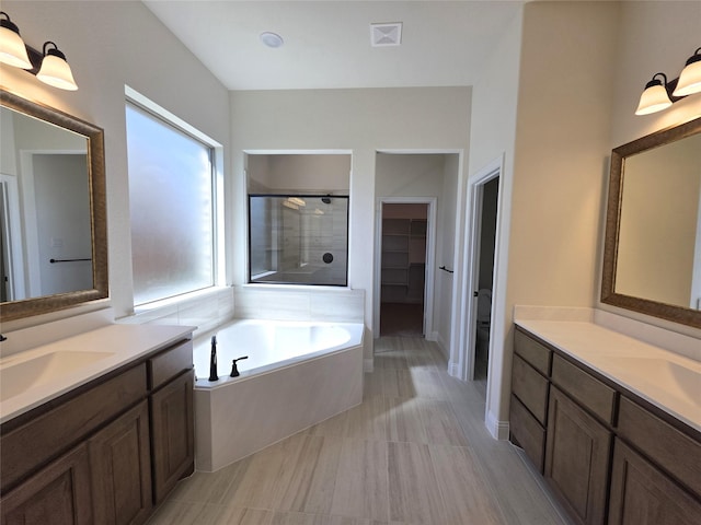 bathroom featuring a garden tub, visible vents, a sink, and a stall shower