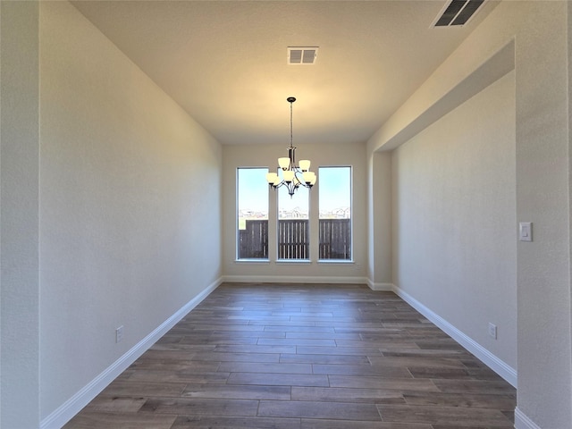unfurnished dining area with dark wood-style floors, baseboards, a chandelier, and visible vents