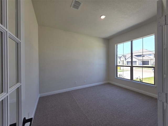 empty room featuring baseboards, visible vents, and carpet
