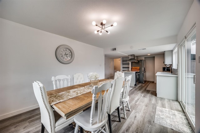 dining room with a notable chandelier, sink, and light wood-type flooring