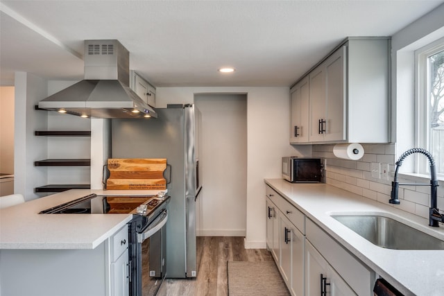 kitchen featuring sink, decorative backsplash, island exhaust hood, electric range, and light hardwood / wood-style floors