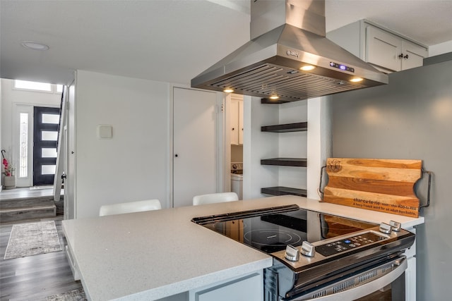 kitchen with island exhaust hood, light stone countertops, dark hardwood / wood-style flooring, and stainless steel electric range