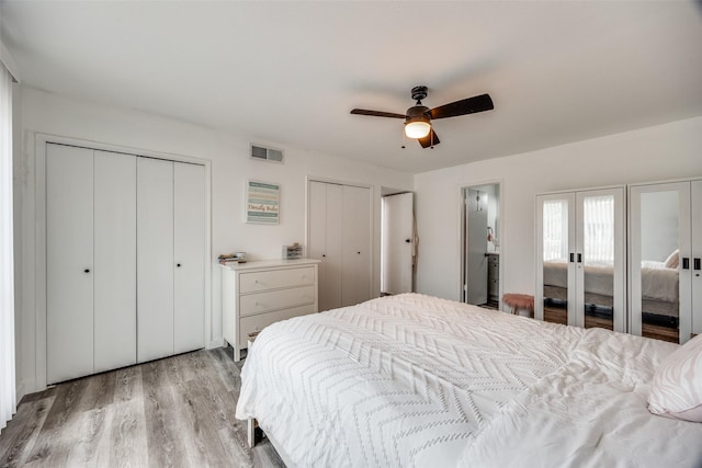 bedroom featuring two closets, ceiling fan, and light wood-type flooring