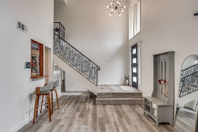 entrance foyer featuring hardwood / wood-style flooring, a high ceiling, and a notable chandelier