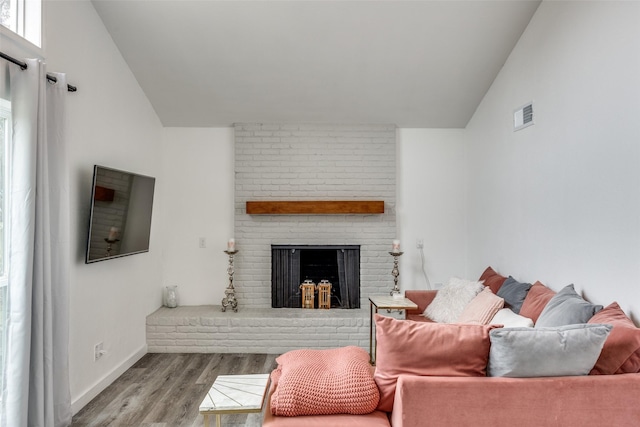 living room featuring lofted ceiling, a fireplace, and light wood-type flooring