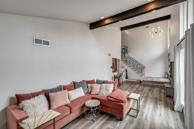 living room with beam ceiling, wood-type flooring, a chandelier, and a high ceiling