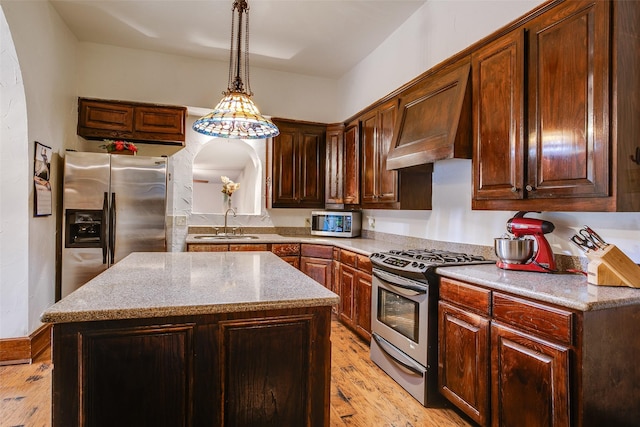 kitchen featuring sink, stainless steel appliances, a center island, custom range hood, and decorative light fixtures