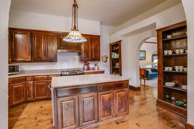 kitchen with stove, a center island, light hardwood / wood-style floors, and decorative light fixtures