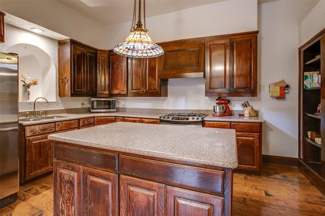 kitchen featuring sink, wood-type flooring, a kitchen island, pendant lighting, and stainless steel appliances