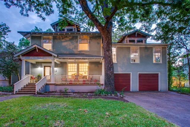 view of front of home with a garage, a front yard, and a porch