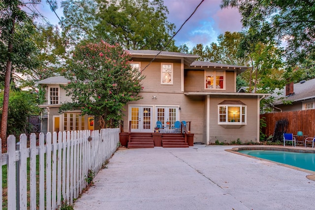 back house at dusk featuring a patio, french doors, and a swimming pool side deck