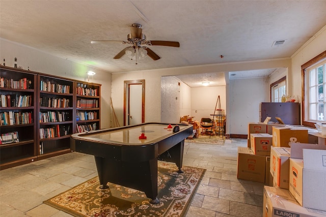 game room with ceiling fan, ornamental molding, and a textured ceiling