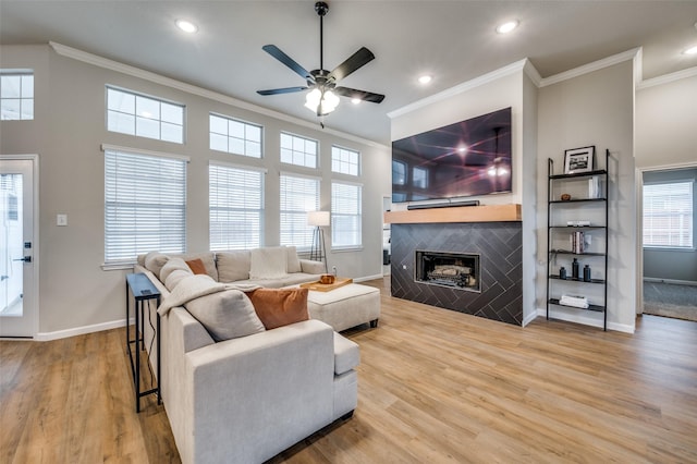 living area featuring baseboards, a tiled fireplace, ornamental molding, recessed lighting, and wood finished floors