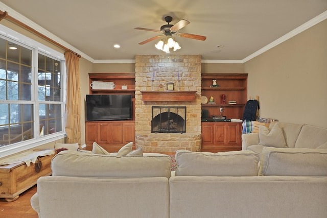 living room featuring crown molding, a stone fireplace, ceiling fan, and light hardwood / wood-style floors