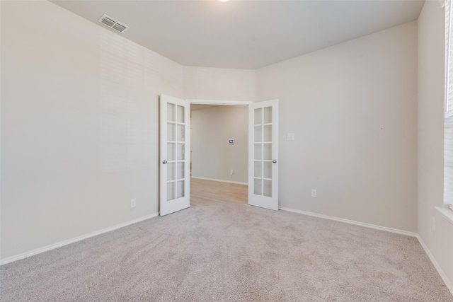 unfurnished room featuring french doors and light carpet