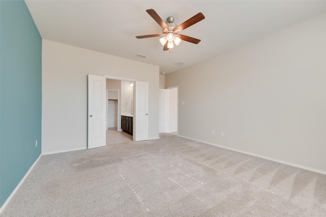 unfurnished bedroom with ceiling fan, ensuite bathroom, and light carpet