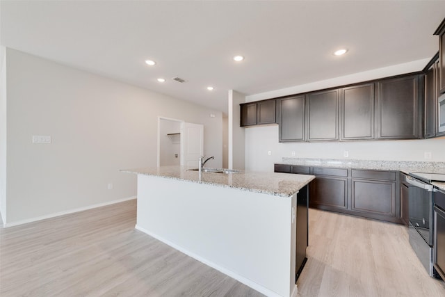 kitchen featuring sink, stainless steel electric range oven, a center island with sink, light hardwood / wood-style flooring, and light stone countertops