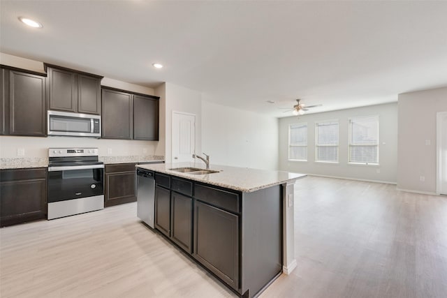 kitchen featuring sink, dark brown cabinets, light wood-type flooring, stainless steel appliances, and a kitchen island with sink