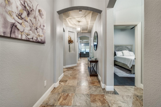15805 Rockingham St, Frisco, TX 75036 - hallway featuring arched walkways, a textured wall, stone finish flooring, and baseboards