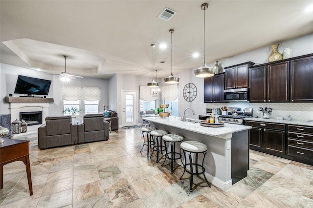 15805 Rockingham St, Frisco, TX 75036 - kitchen with stainless steel appliances, ceiling fan, a kitchen bar, open floor plan, and decorative backsplash