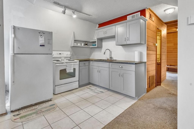 kitchen with gray cabinets, sink, light carpet, and white appliances