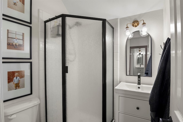 bathroom featuring vanity, toilet, and a shower with shower door