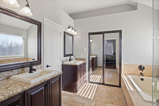 bathroom with vanity and tiled tub