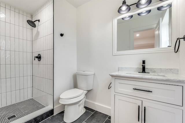 bathroom with vanity, a tile shower, tile patterned floors, and toilet